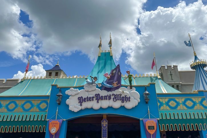 Image of the outside of Peter Pan's Flight. The buildings look like circus tents and the sign is done in a story book script. 