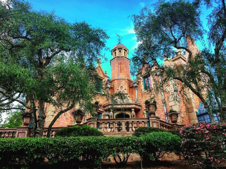 An image of the Haunted Mansion through trees.