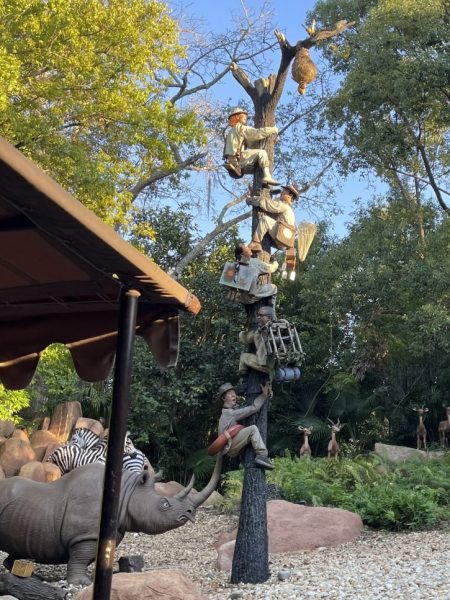 Image from the Jungle Cruise with animatronic skippers climbing up a dead tree to escape a rhinoceros.