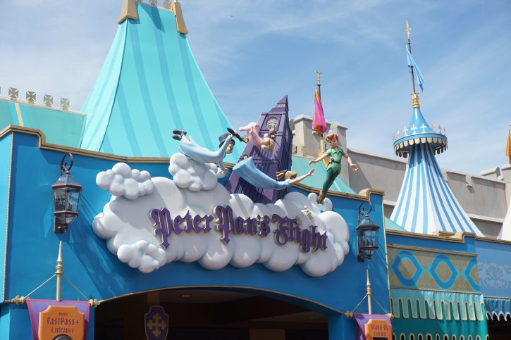 Image of the sign for Peter Pan's flight above the entrance for the queue. Statues of the Darling childran and Peter Pan float above it making it look like they are flying.