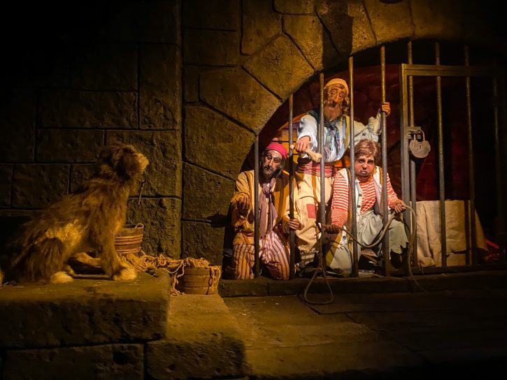 Pirate animatronics reaching through jail bars with a bone to try and entice an animatronic dog with a key in it's mouth to them. This scene comes from the end of the Pirates at the Caribbean ride. 