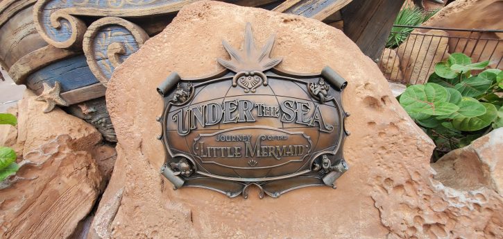 Metal sign outside Under the Sea - Journey of the Little mermaid ride. The sign is done in the style of old sea maps. 